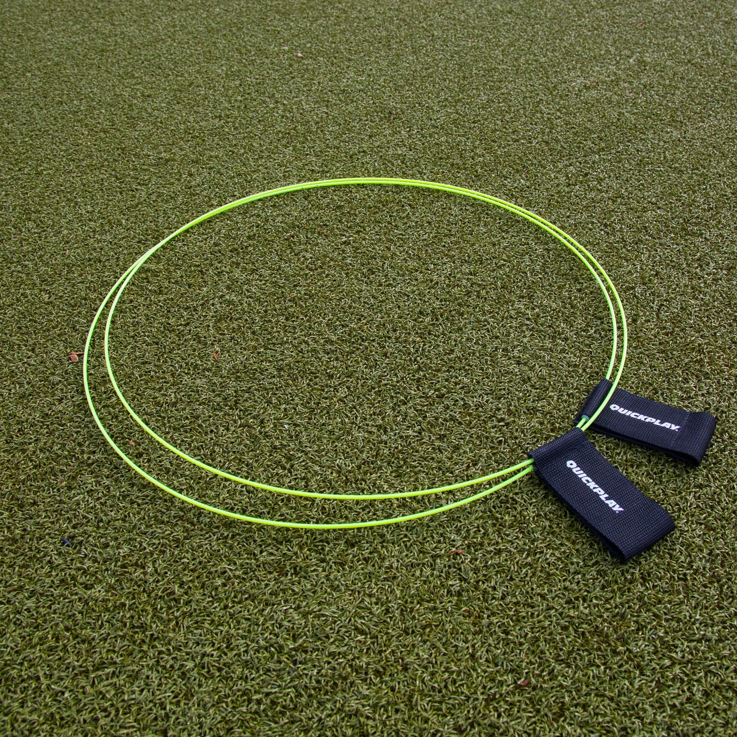 Anelli bersaglio KICKSTER (set di 2) distesi su erba sintetica, due anelli gialli con cinghie nere QUICKPLAY.