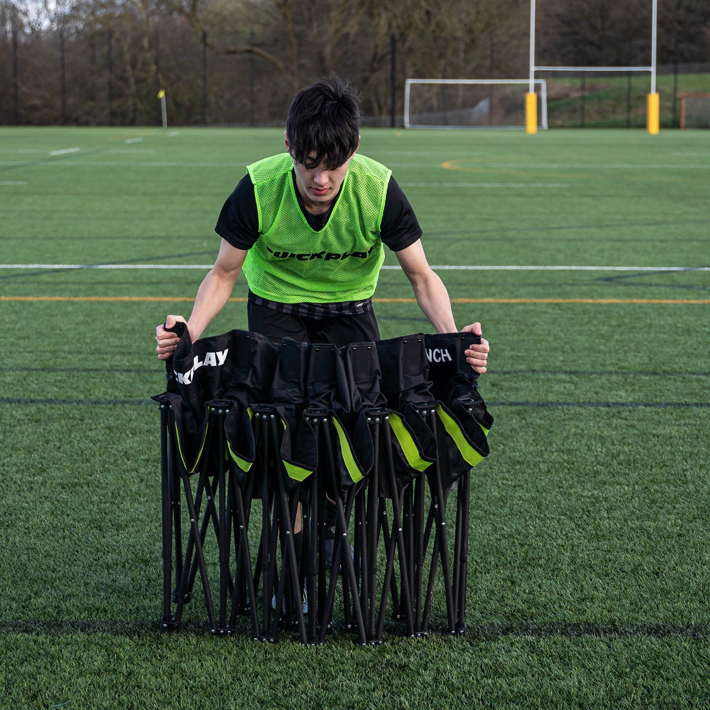 Giocatore con una casacca verde QUICKPLAY e la panchina PRO Bench 9 posti parzialmente chiusa davanti a sé su un campo.