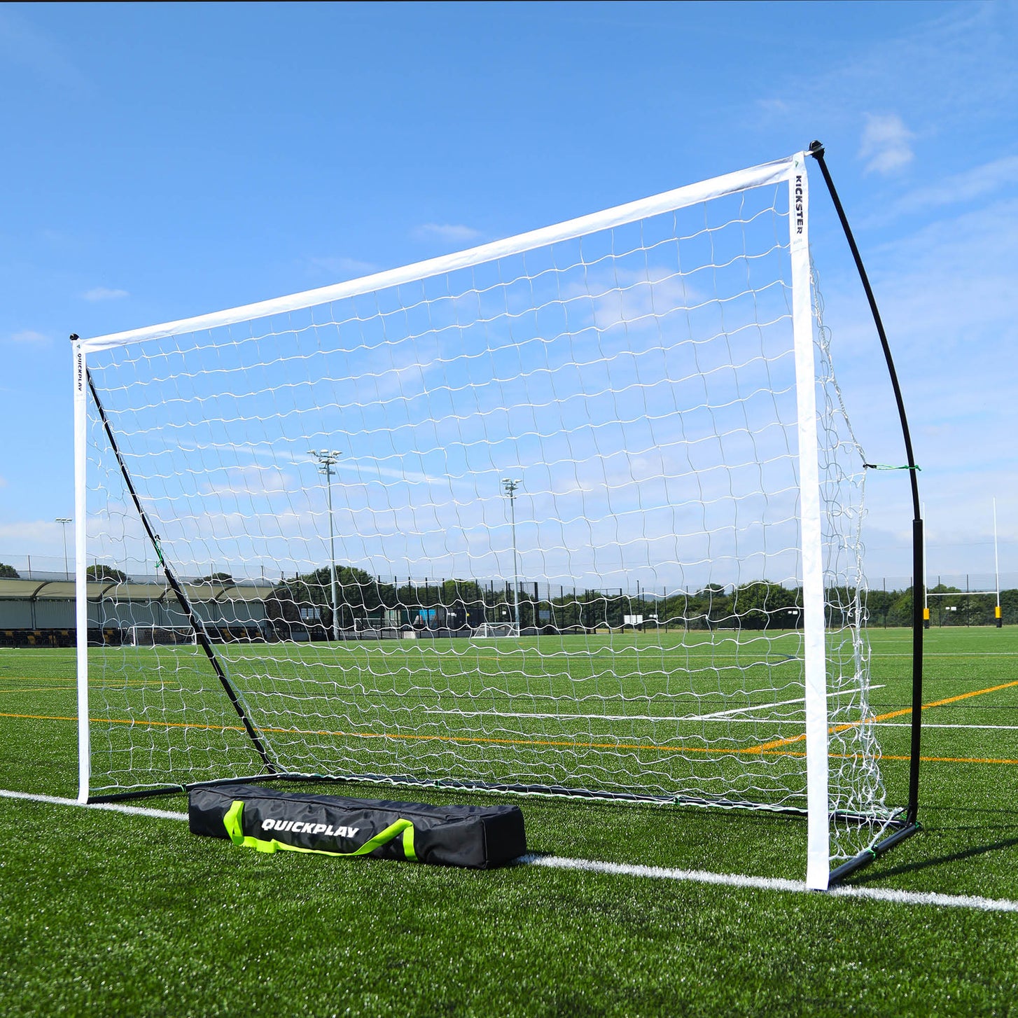 Porta da calcio a 5 KICKSTER Elite 300 x 200 cm montata su un campo in erba sintetica, con la sua borsa nera QUICKPLAY davanti.