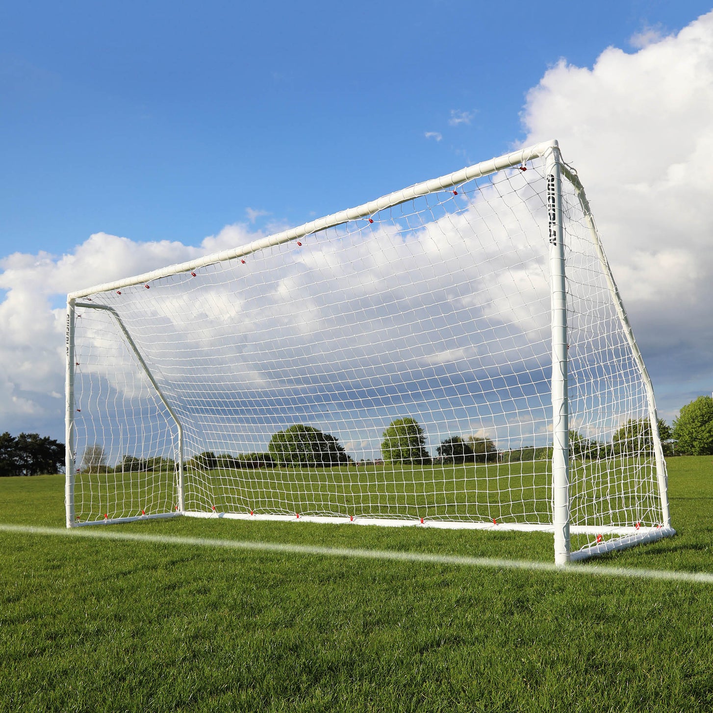 Porta da calcio pieghevole Q-FOLD Match 370 x 180 cm con telaio e rete bianchi, sull'erba sotto un cielo azzurro con nuvole.