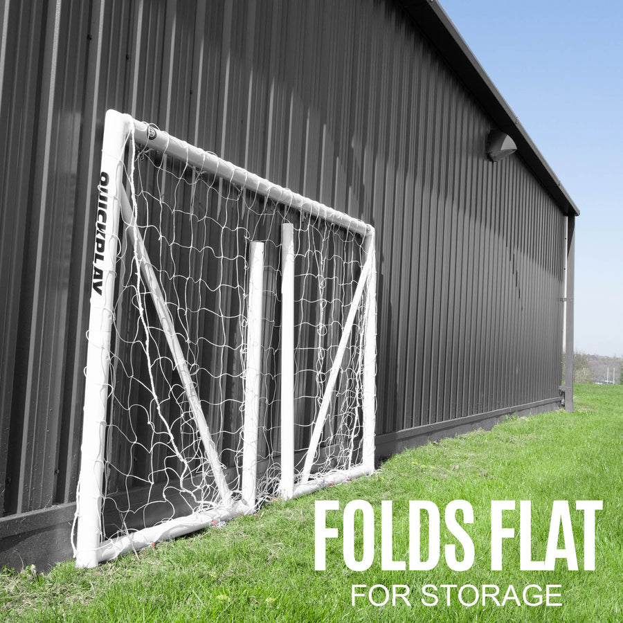 Porta Q-FOLD 240 x 150 cm ripiegata e appoggiata contro un edificio scuro in metallo, con la scritta "folds flat for storage".