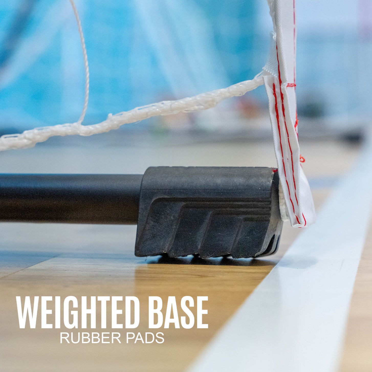 Primo piano della base della porta da pallamano portatile per bambini 240 x 170 cm sul pavimento di un palazzetto, con la scritta "weighted base, rubber pads".