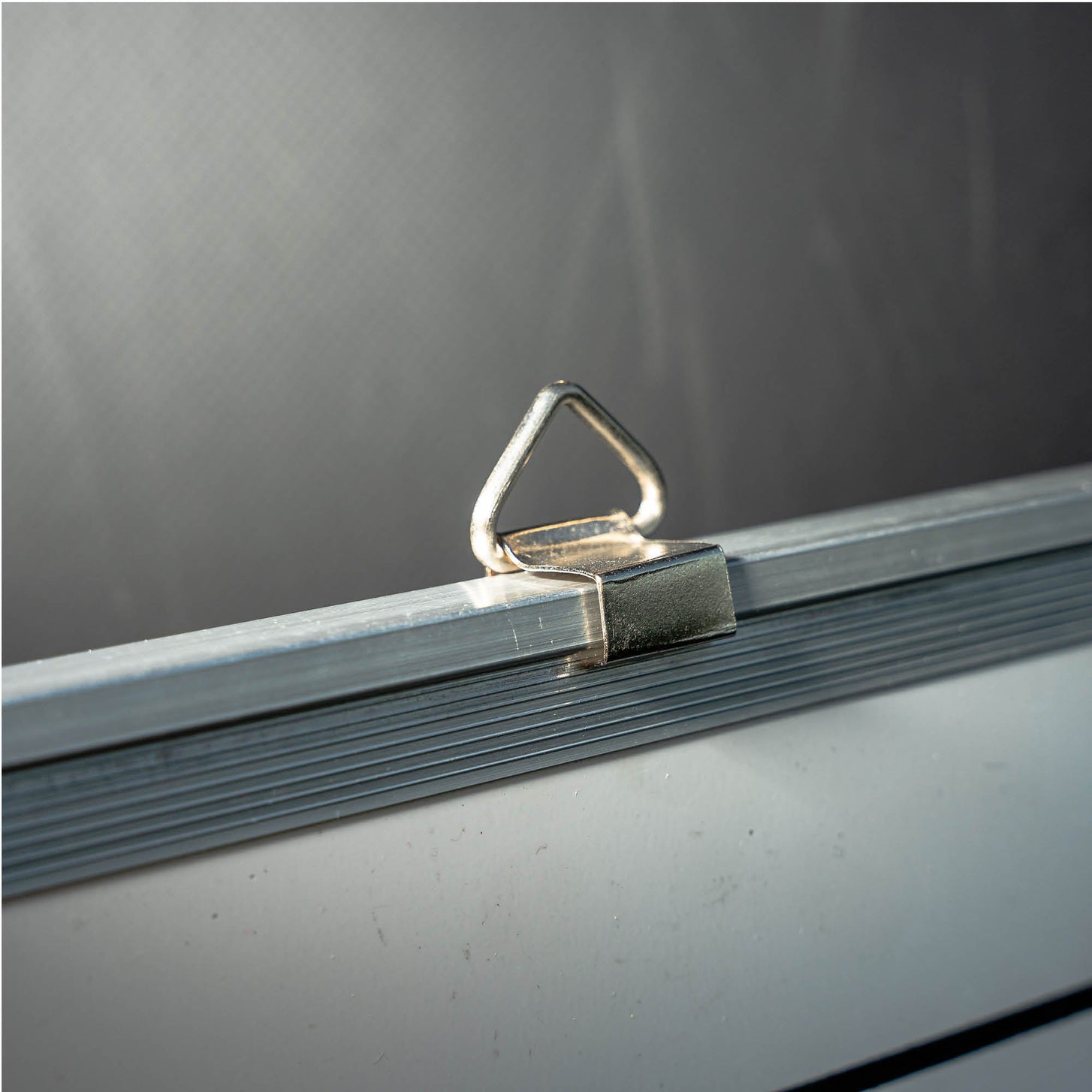 Primo piano di un anello metallico per appenderla sul bordo superiore della cornice della lavagna tattica magnetica da calcio 60 x 90 cm.