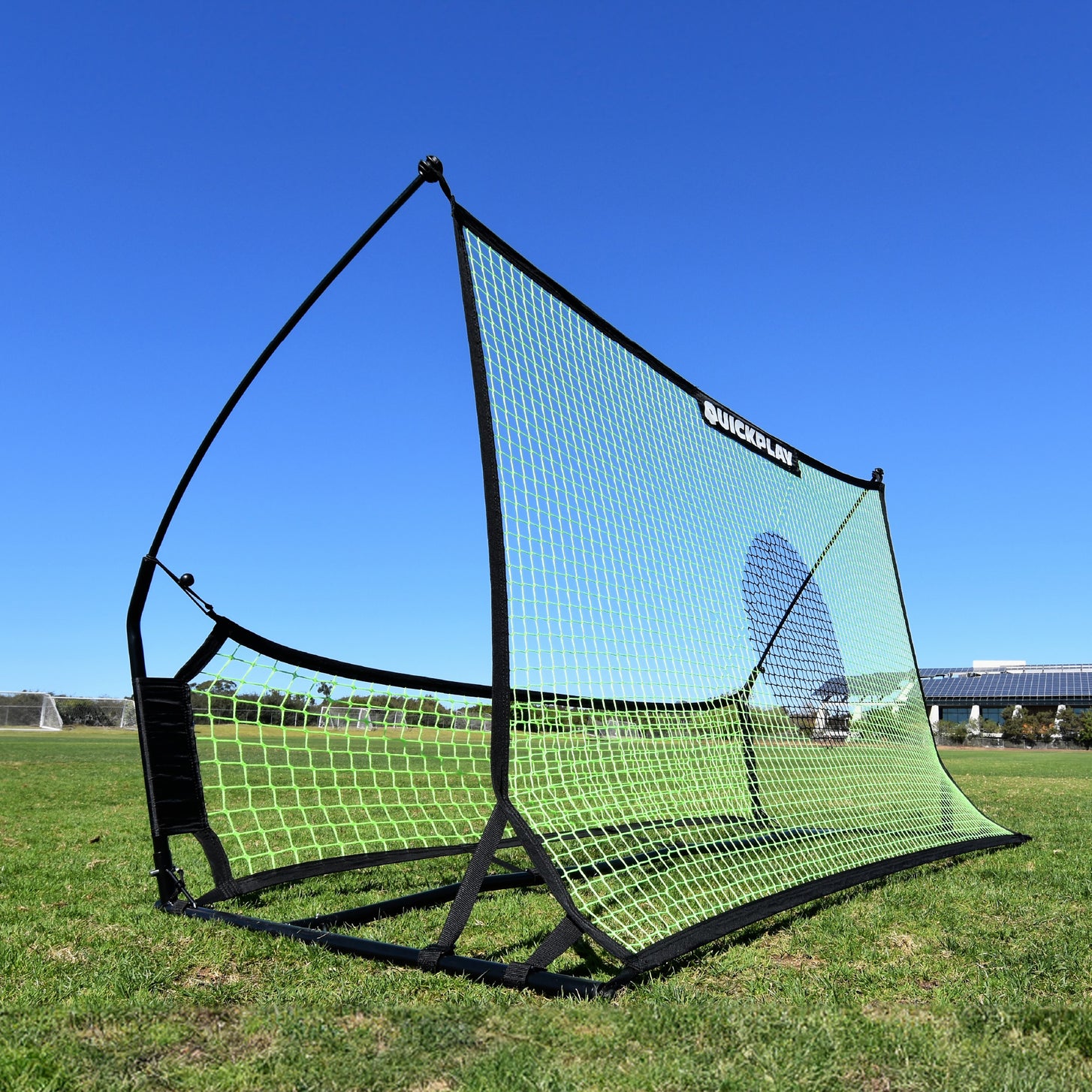 Rebounder da calcio a doppia rete TEKKERS Trainer sull'erba, con la grande rete verde con un cerchio bersaglio scuro e la rete inferiore.