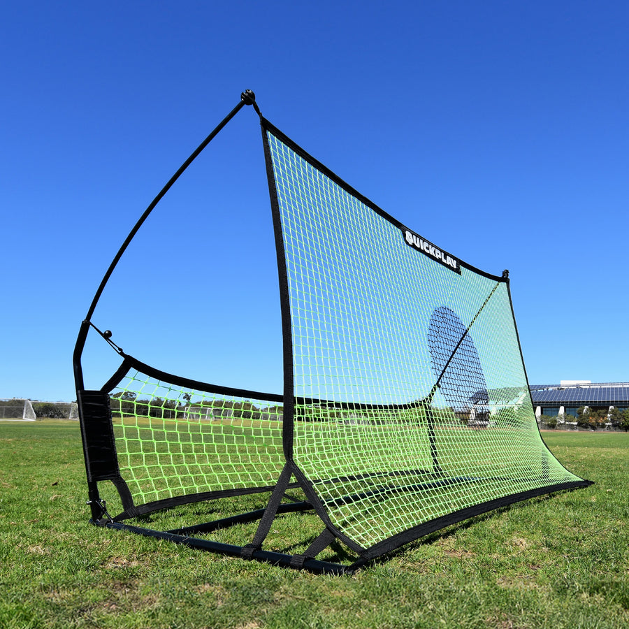 Rebounder da calcio a doppia rete TEKKERS Trainer sull'erba, con la grande rete verde con un cerchio bersaglio scuro e la rete inferiore.