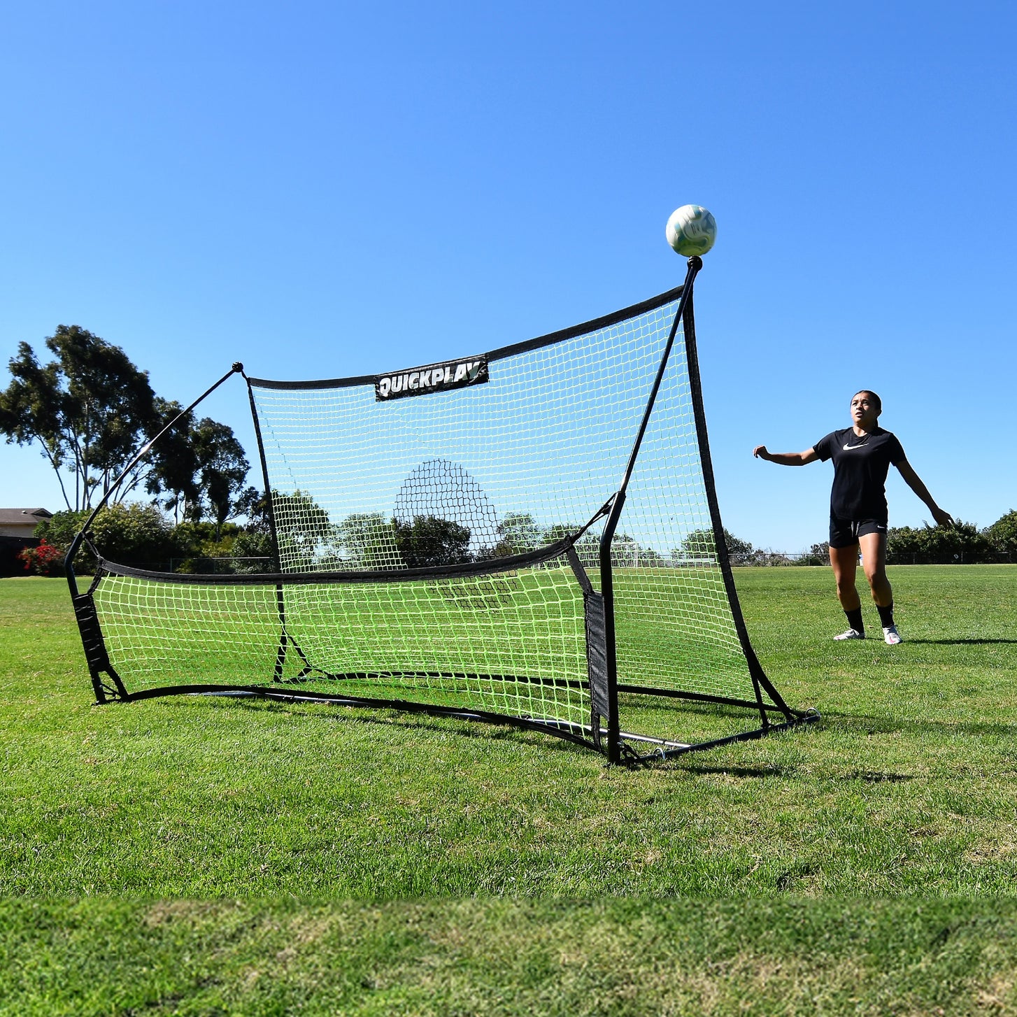 Giocatore che attende una palla che rimbalza verso l'alto dal rebounder da calcio a doppia rete TEKKERS Trainer su un campo in erba.