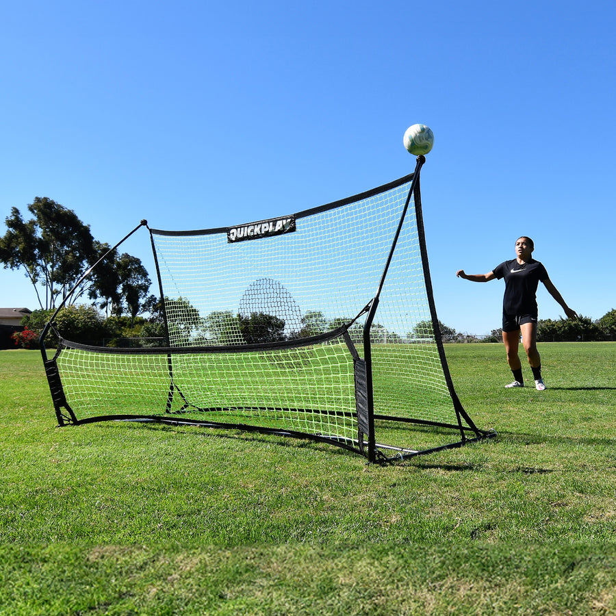 Giocatore che attende una palla che rimbalza verso l'alto dal rebounder da calcio a doppia rete TEKKERS Trainer su un campo in erba.